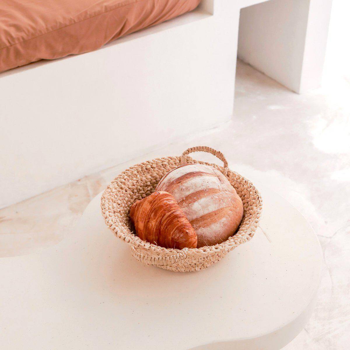 Handgemaakte gevlochten raffia schaal met stokbrood en croissant, decoratief en duurzaam.