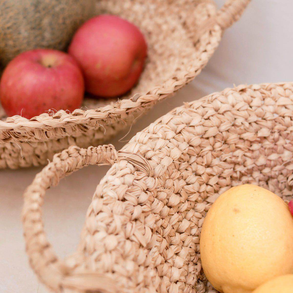 Geweven raffia fruitschaal met appels en citrus, handgemaakt en duurzaam design, perfect voor keuken of tafeldecoratie.