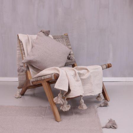 Alt Tag: Stijlvolle houten stoel met taupe pompom deken en kussen, perfect voor een boho interieur en gezellige avonden.